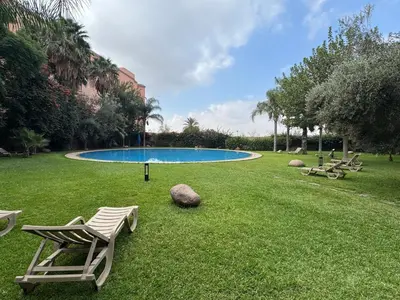 a lawn with two chairs and a swimming pool at Cozy apartment in city center in Marrakech