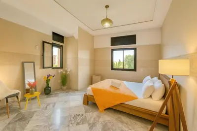 a bedroom with a bed and a chair and windows at Luxurious M avenue Hivernage - next to Pestana CR7 in Marrakech