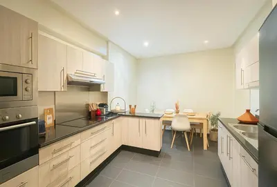 a kitchen with white cabinets and a dining table at Luxurious M avenue Hivernage - next to Pestana CR7 in Marrakech