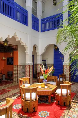 a room with a table and chairs and a blue door at Riad Dar Colline in Marrakech