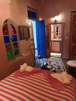 a bedroom with a bed and a blue door and a bathroom at Riad Dar Colline in Marrakech