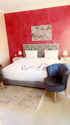 a bedroom with a large bed with a red wall at Lot tichka villa n6 in Marrakech