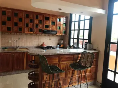 a kitchen with wooden cabinets and bar stools at Lot tichka villa n6 in Marrakech