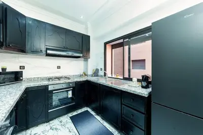 a kitchen with black cabinets and a black refrigerator at Oasis exclusive avec piscine dans le centre-ville in Marrakech
