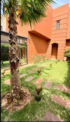 a palm tree in front of a house at Charmant villa au cœur de la palmeraie in Douar Caïd Layadi