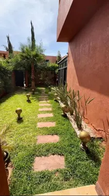 a garden with a stone walkway next to a building at Charmant villa au cœur de la palmeraie in Douar Caïd Layadi