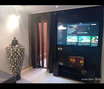 a living room with a large television and a vase at Chic et Cosy deux chambres avec Piscine in Marrakech