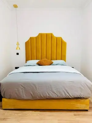 a bed with a large wooden headboard in a bedroom at HIVER NAGE home in Marrakech