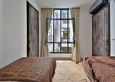 a bedroom with two beds and a large window at Riad dar Tayri in Marrakech