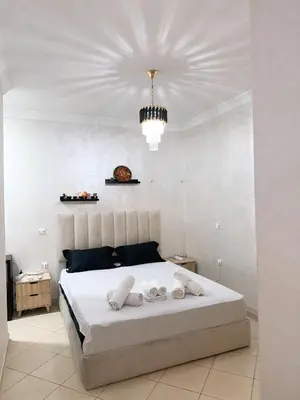 a bedroom with a large white bed with a chandelier at Appartement Xénon in Marrakech
