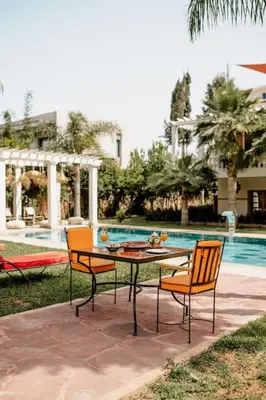 a patio with a table and two chairs and a pool at La Villa d'Oz pour 12 personnes Golf Amelkis in Marrakech
