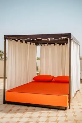 an orange bed with a canopy and two red pillows at La Villa d'Oz pour 12 personnes Golf Amelkis in Marrakech