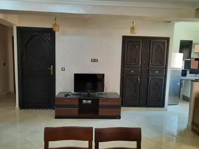 a living room with two large wooden doors and a television at Appartement avec piscine Guéliz in Marrakech