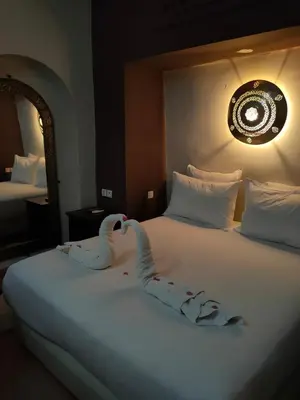 two swans sitting on a bed in a hotel room at Riad shéhérazade Marrakech in Marrakech
