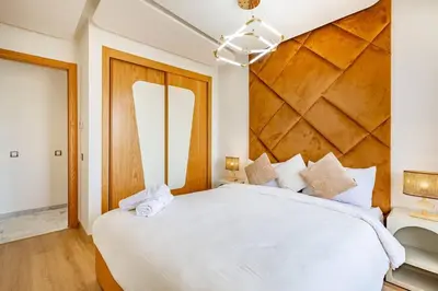 a bedroom with a large white bed with a wooden headboard at New! Appt Riad Garden, piscine & wifi & parking in Marrakech