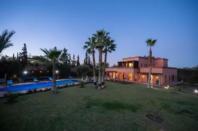 a house with a yard with a pool and palm trees at Villa 5 suits with pool and montains view in Sraghna