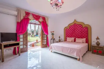 a bedroom with a bed with a red headboard and a tv at Villa 5 suits with pool and montains view in Sraghna