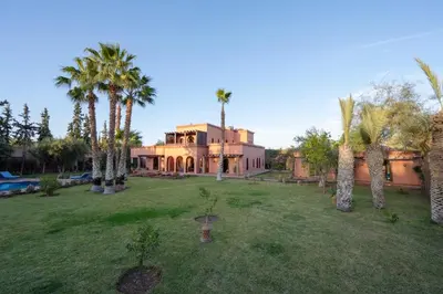 a large house with palm trees in the yard at Villa 5 suits with pool and montains view in Sraghna