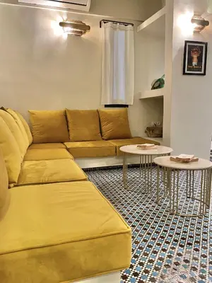 a living room with a yellow couch and tables at Riad Dardeco privé centre Medina Marrakech in Marrakech