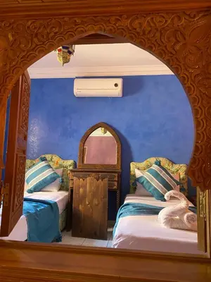 two beds in a room with blue walls at Riad Tichka piscine palmeraie in Marrakech