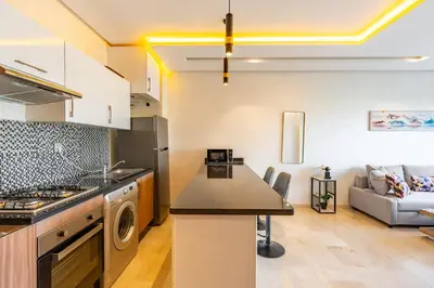 a kitchen and a living room with a couch at Relax Front of Pool - Golf- Fiber Optic in Marrakech