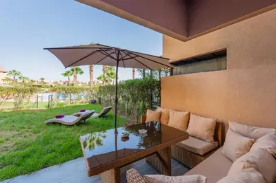 a living room with a couch and an umbrella at Relax Front of Pool - Golf- Fiber Optic in Marrakech