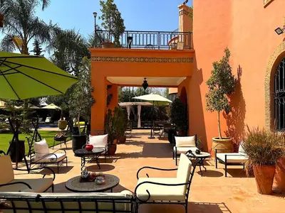 an outdoor patio with chairs and tables and umbrellas at Palais Ona in Marrakech