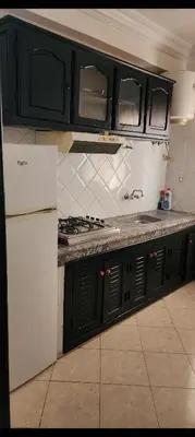 a kitchen with black cabinets and a white refrigerator at Apparemment a Marrakech très agr in Marrakech