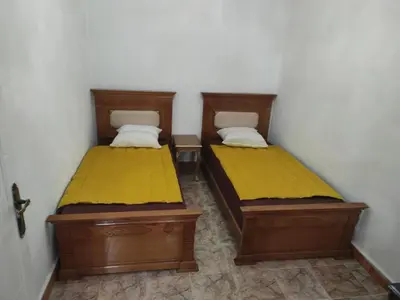 two twin beds in a room with yellow sheets at Appartement de luxe in Marrakech