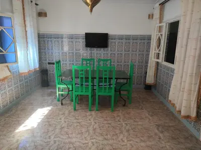a dining room with green chairs and a table at Appartement de luxe in Marrakech