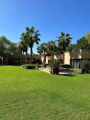 a lawn with palm trees in front of a building at Villa Albatros in Marrakech