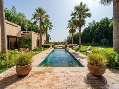 a swimming pool in a yard with palm trees at Villa Albatros in Marrakech