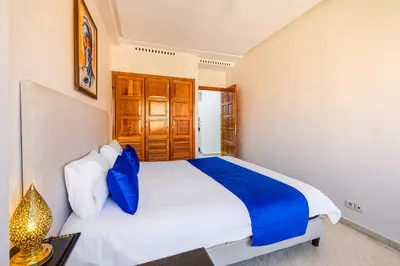 a bedroom with a large white bed with blue pillows at Appartement Marrakech - quartier Gueliz in Marrakech