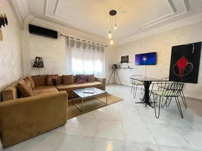 a living room with a couch and a table at La rose à côté Carry in Marrakech