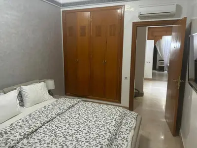 a bedroom with a bed and a wooden cabinet at Beautiful cozy apartment with pool in Marrakech