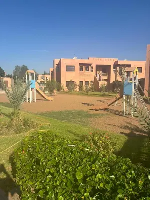 a park with a playground with a slide and a building at Beautiful cozy apartment with pool in Marrakech