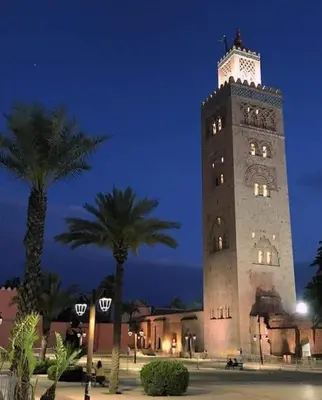 a large clock tower with palm trees in front of it at Jardin Majorelle Appartement in Marrakech