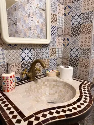 a bathroom with a sink and a mirror and tiles at Julie Airport Marrakech Apartments in Marrakech