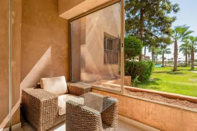 a balcony with a chair and a large window at Elegant Apartment in Prestigia Golf Marrakech in Marrakech