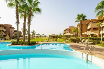 a swimming pool at a resort with palm trees at Elegant Apartment in Prestigia Golf Marrakech in Marrakech
