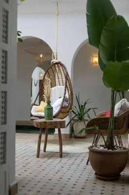 a room with a swing chair and a table with plants at Riad Lamalika in Marrakech