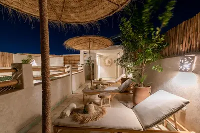 a resort patio with chairs and tables and a umbrella at Riad Lamalika in Marrakech