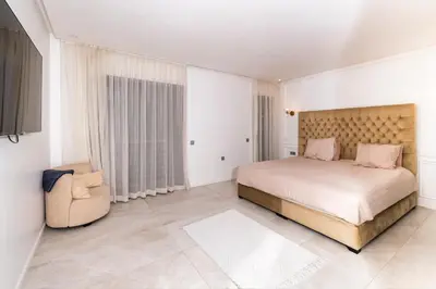 a bedroom with a large bed and a chair at Menara Garden duplex 3 suites in Marrakech
