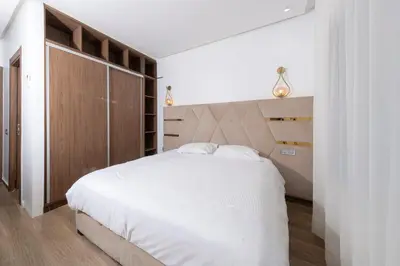 a bedroom with a large white bed with a wooden headboard at Menara Garden duplex 3 suites in Marrakech