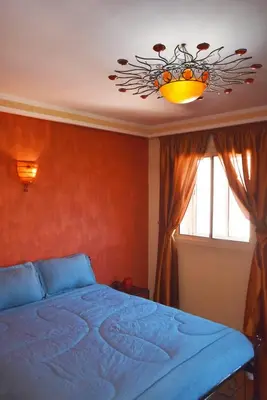 a bedroom with a blue bed and a chandelier at Appartement au Coeur de quartier Majorelle in Marrakech