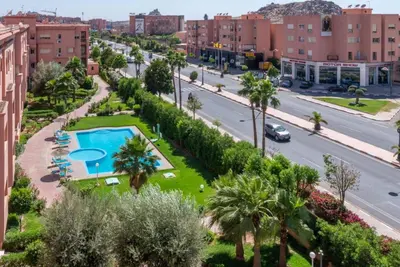 a city street with a pool and palm trees at Appartement au Coeur de quartier Majorelle in Marrakech