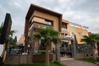 a building with a palm tree in front of it at Jawhar Appart in Marrakech