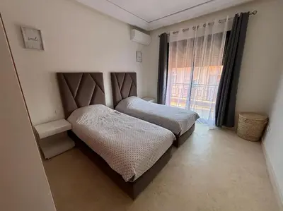 a bedroom with two beds and a large window at Appartement Piscine à Marrakech in Marrakech