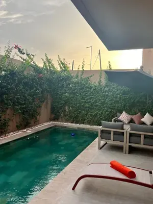 a swimming pool with a couch and a chair next to it at Villa familiale avec piscine chauffée La Dolce Vita in Marrakech