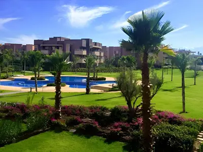 a view of a park with palm trees and a building at l'écrin de prestigia agate studio in Marrakech
